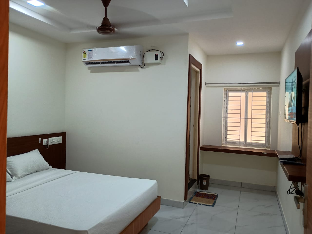 Aditya Inn Standard Room with comfortable queen bed, television, and clean decor.